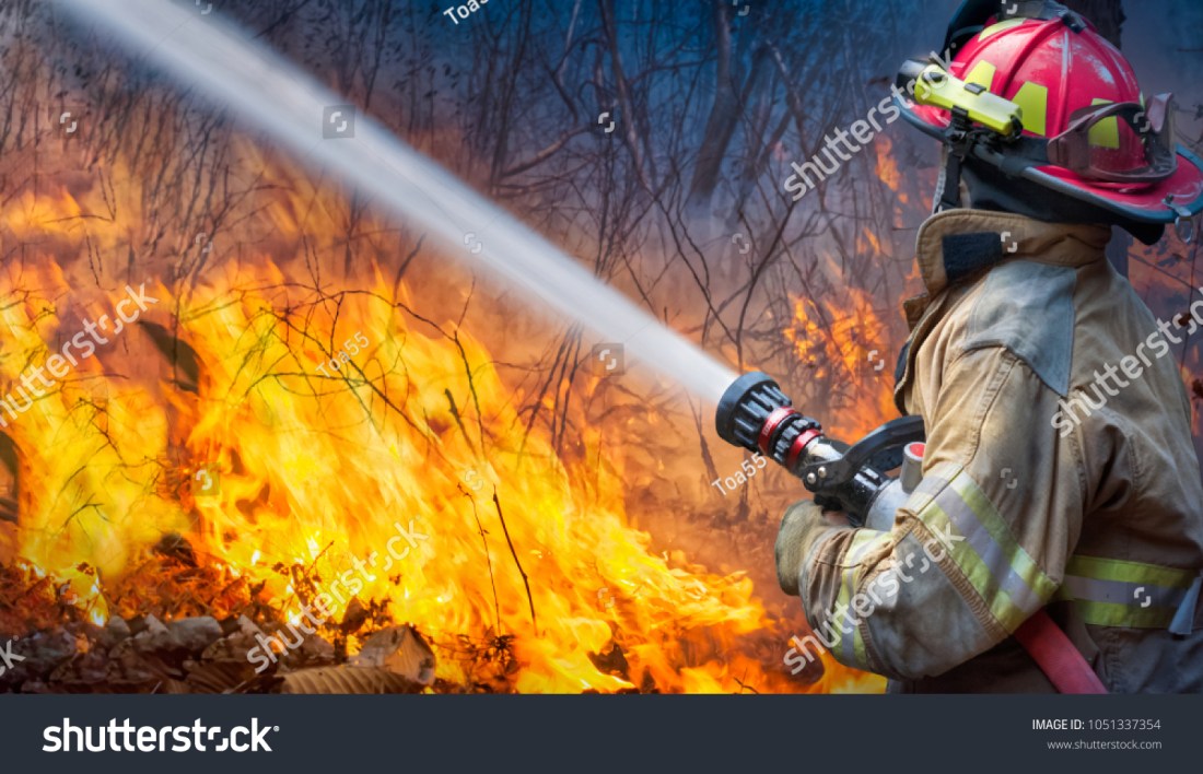 stock-photo-natural-disaster-firefighters-spray-water-to-wildfire-1051337354